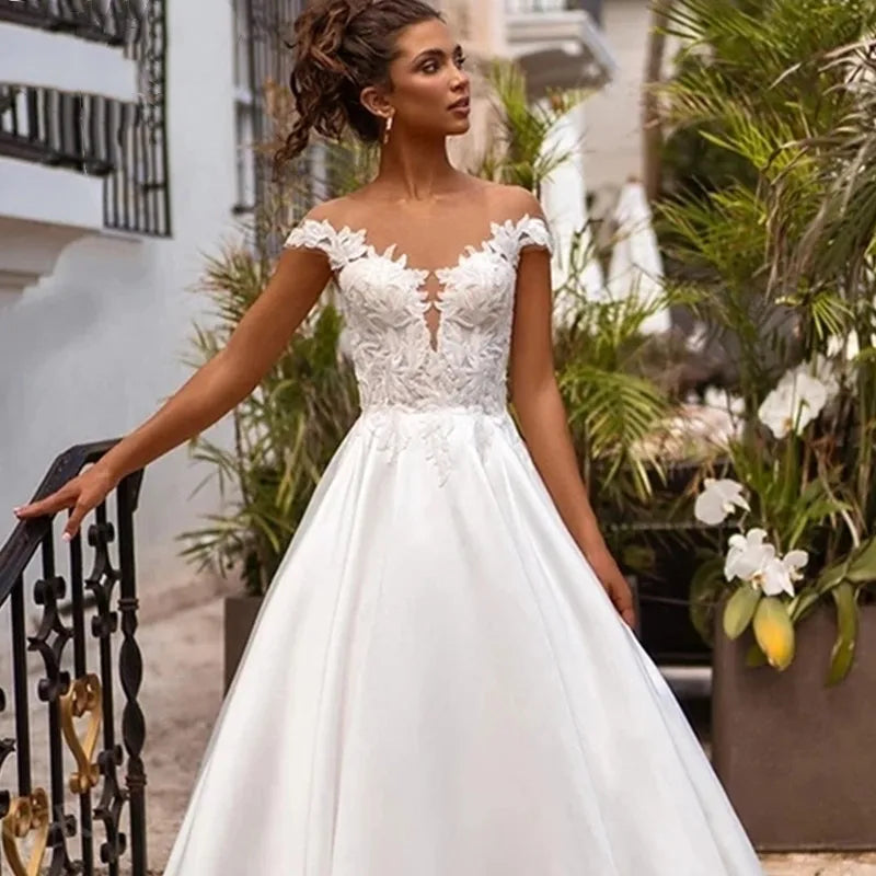 Elevate your wedding day look with the Robe Joanne. Featuring delicate lace appliques, modern satin fabric, and elegant cap sleeves, this dress offers a timeless and sophisticated style for any bride. Say "I do" in comfort and confidence with this stunning and versatile wedding dress.
