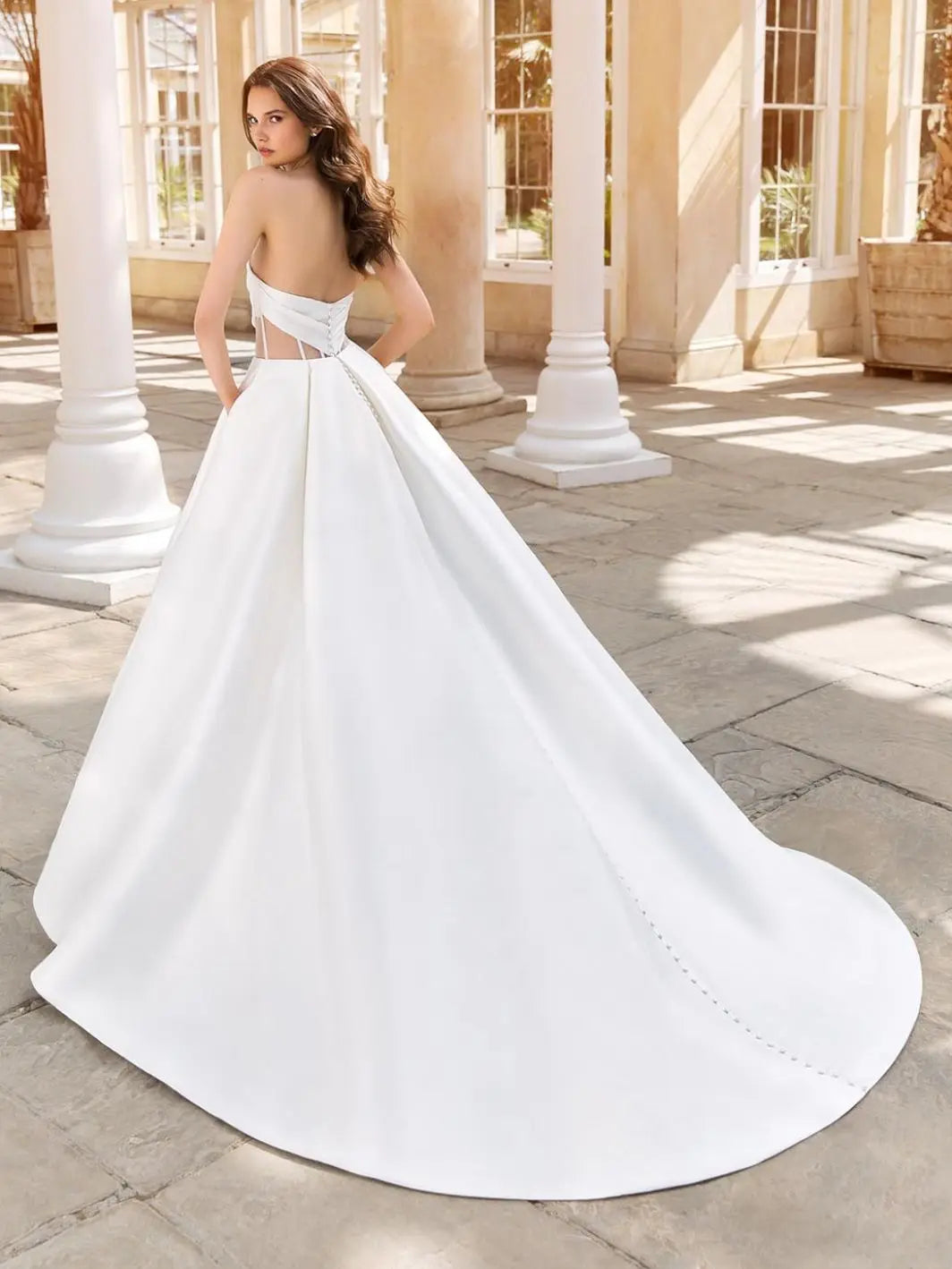 This 2-in-1 wedding dress offers versatility and style for a bride on her special day. It features a detachable ball gown with an off-shoulder design and a long, sheer tail for a dramatic entrance. The pleated bodice adds a touch of elegance and glamour, making it the perfect dress for any bride.