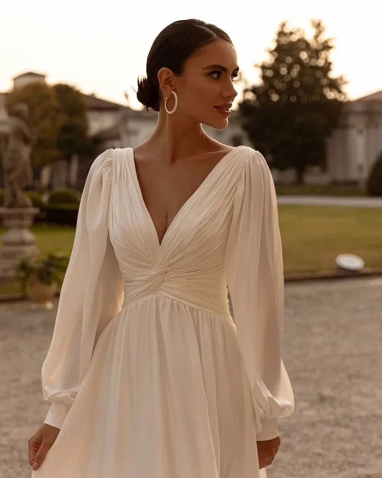 Embrace your inner bohemian goddess with Dress Michelle. The flowy chiffon and long sleeves create a dreamy A-line silhouette, perfect for a custom-made wedding dress. Add a touch of whimsy with the sweep train, making you feel like a true boho bride. Let your free-spirited style shine on your special day.