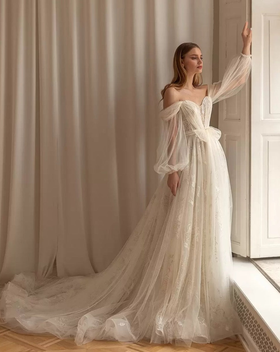 This stunning Robe Annalisa is the perfect choice for any bride-to-be. With a sweetheart neckline, full sleeve design, and beautiful bow detail, it combines elegance and femininity. The A-line silhouette flatters any body type, making you feel confident and gorgeous on your special day. Complete your look with this must-have wedding dress.