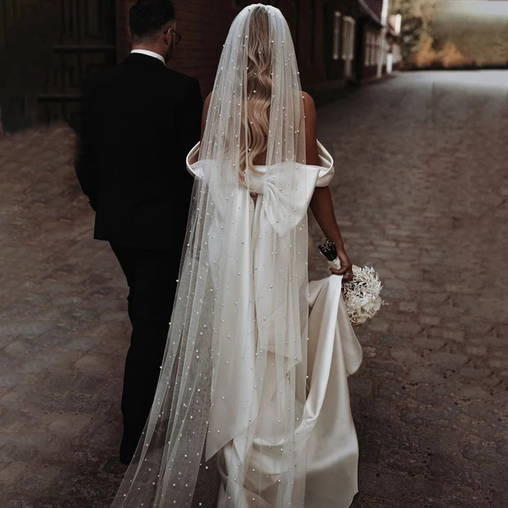 Introducing the Robe Rafaella - the perfect wedding dress for the modern bride. This elegant off shoulder sheath dress features a removable bow and is custom made to ensure the perfect fit. Made with thick satin, it offers a simple and timeless look while providing comfort and support. Say "I do" in style with the Robe Rafaella.