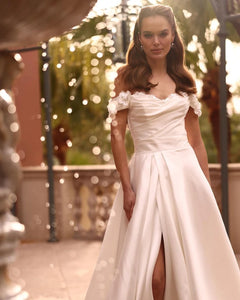 Indulge in luxury and elegance with our Robe Joie. Designed with an off the shoulder neckline, flower details, and soft satin material, this bridal gown exudes sophistication. The side split and corset back add a touch of sensuality, perfect for the modern bride. Elevate your wedding day with this exclusive dress.
