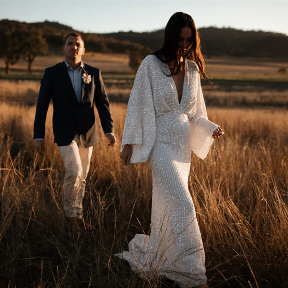 Robe Severine is an exquisite wedding dress tailored to perfection. Richly detailed with lustrious sequined V-neck and long batwing sleeves, it is tailored for an unforgettable bridal gown experience. Its custom-made overweight sizing ensures a comfortable fit and its crystals add a graceful touch to this elegant gown.