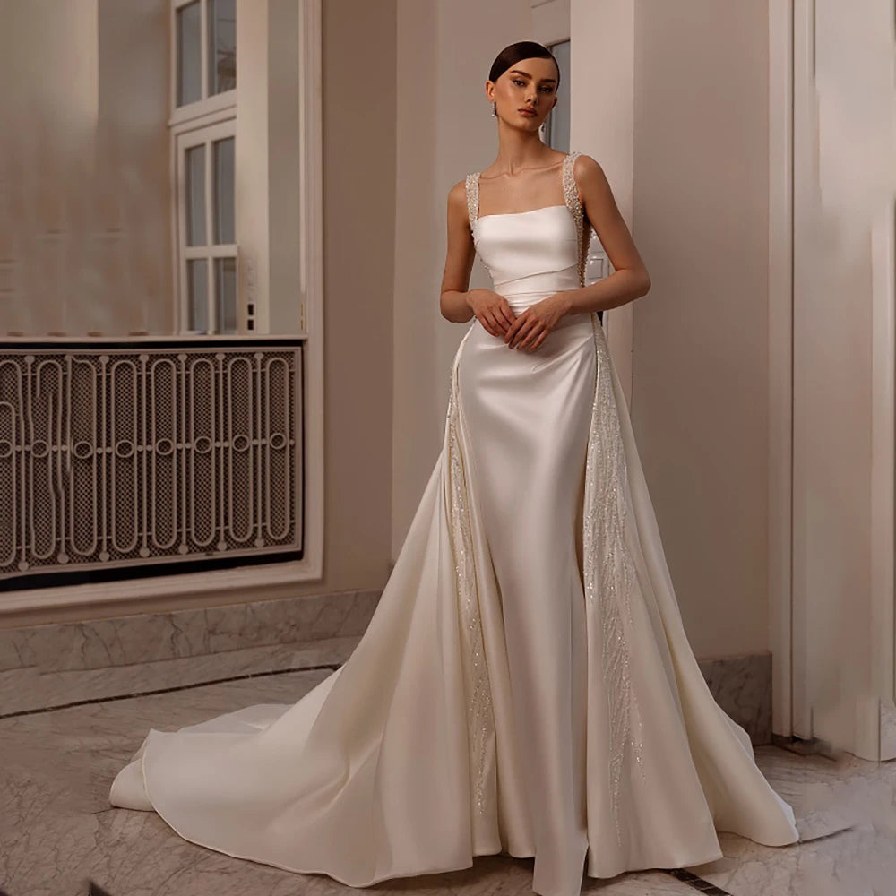 Indulge in luxury with our Robe Angeline. This bridal gown features a square neckline and elegant beading, perfectly complimented by a removable train. The custom cutouts and backless design add a touch of sophistication. Make a memorable entrance on your special day with the Robe Angeline.