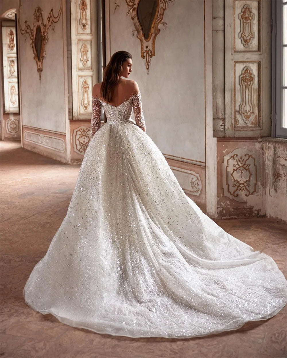 Indulge in luxury with the Robe Suzette. This elegant A-line wedding dress features an illusion neck, long sleeves, and intricate beading and pearls. Graceful and sophisticated, it's perfect for the modern bride. Complete your look with this designer gown and feel confident and stunning on your special day.