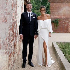 Look red-carpet ready in the captivating Sigourney robe. Featuring off-shoulder cape sleeves, a vintage crepe bodice, and a bias split open back with buttons, this gown makes an unforgettable statement. Custom made with an oversized cinched waist, take risks and be your own style icon on your big day.