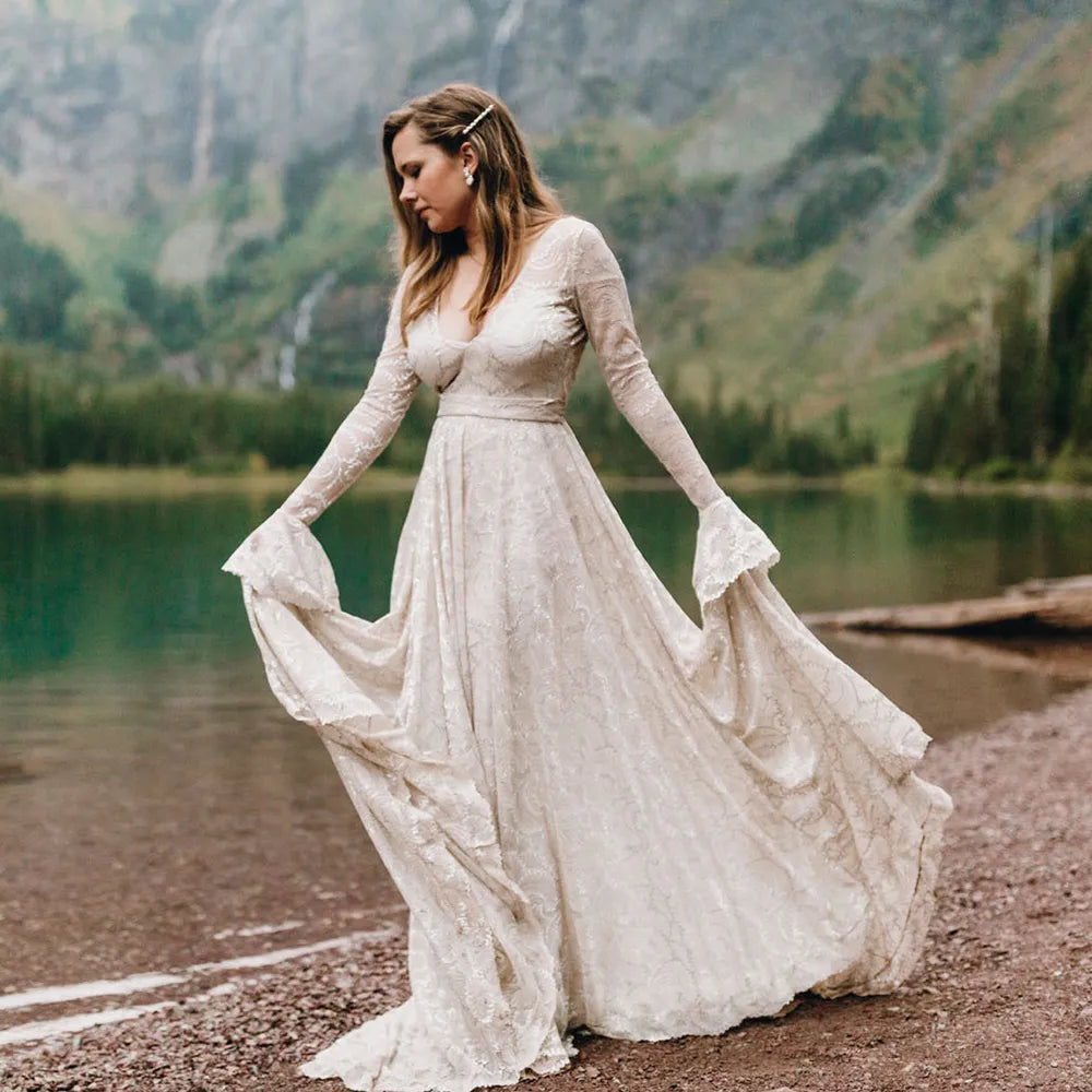 Experience the magic of your special day in our Dress Ava. The boho beach elopement design features long sleeves, a flare backless, and intricate lace with delicate pearls and tassels. The A-line silhouette and V-neckline are complemented by a custom-made belt for a perfect fit. Say "I do" in style with this unique and stunning bridal gown.