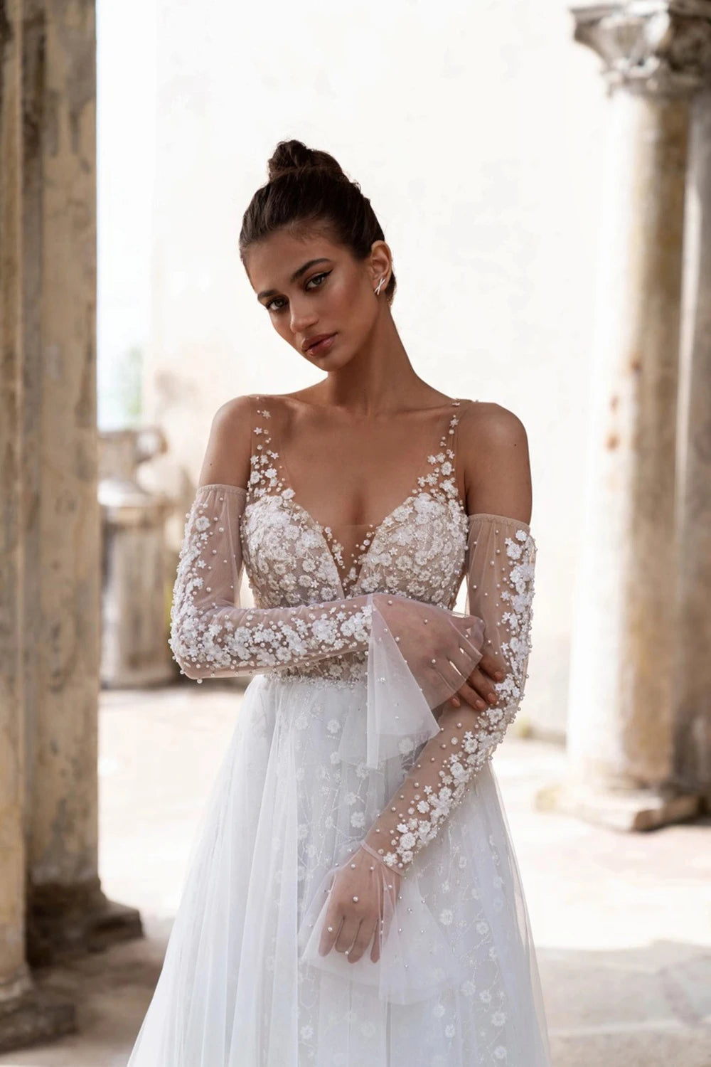 Unleash your inner boho goddess with our Robe Linnet! This stunning V-neck wedding gown features delicate dotted tulle, detachable sleeves, and ruched details for a dreamy, ethereal look. Perfect for the free-spirited bride who loves a touch of whimsy on her special day. Say 'I do' to the Robe Linnet!