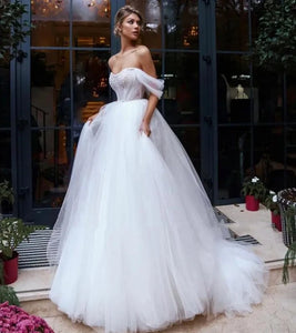 Elevate your wedding day look with our Robe Melina. This elegant ball gown boasts intricate beading, an off the shoulder sweetheart neckline, and a sleeveless tulle design. Perfect for the sophisticated bride seeking a touch of luxury and glamour.