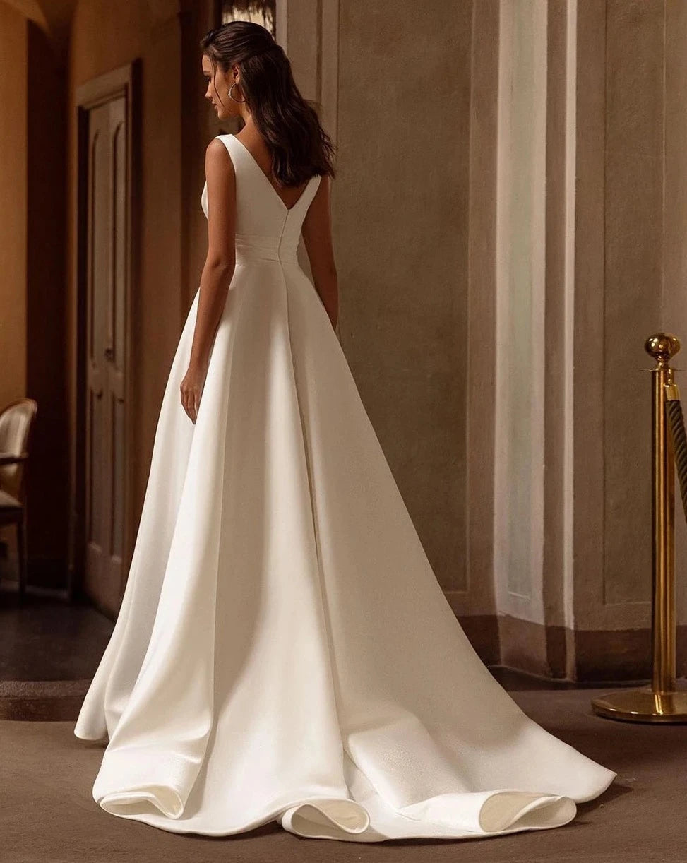 Indulge in the opulent elegance of the Robe Loire. Made with sumptuous satin and featuring a pleated sleeveless design, this V neck bridal dress is perfect for a beach wedding. Its luxurious fabric and sophisticated silhouette will make you feel like the belle of the ball on your special day.