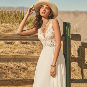 The Dress Scarlett is a stunning bohemian wedding dress designed with a V-neck and delicate lace appliques. The A-line silhouette and flowy chiffon fabric add an ethereal touch, while the backless design and button train bring a modern and romantic twist. Perfect for a boho bride looking for a unique and beautiful gown.