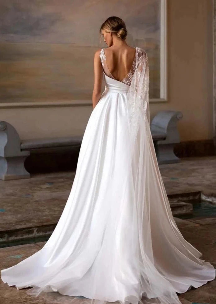 Experience luxurious elegance with our Robe Saira. This exquisite off-shoulder A-line design features playful sleeves and a sexy backless silhouette. Its fluffy texture adds a touch of sophistication to your wedding dress, making you feel confident and glamorous. Elevate your look and make a statement on your special day.