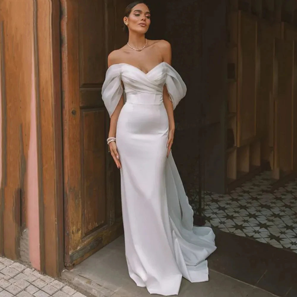 Elevate your special day with our Robe Josy. This stunning satin wedding dress features a sexy backless design and a flattering mermaid silhouette, perfect for highlighting your figure. The off-the-shoulder neckline adds a touch of allure to this gorgeous piece. Walk down the aisle in style with our beautiful and slimming Robe Josy.