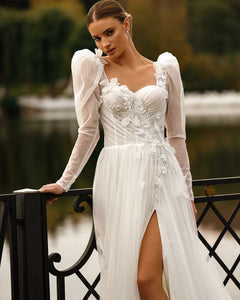 Indulge in luxury with our Robe Sixtine. This elegant Boho wedding dress features delicate lace appliques, an open back, and intricate beading. The long sleeves add a touch of sophistication while the floral details evoke the beauty of a royal wedding. Make a statement on your special day.