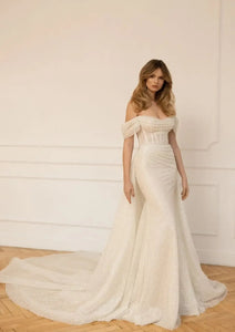 Slay the wedding game in the Robe Claretta! This stunning bridal gown features an elegant boat neckline and off the shoulder design, while the sheath silhouette and ruched details add a touch of sophistication. Get ready to turn heads down the aisle with this show-stopping piece.