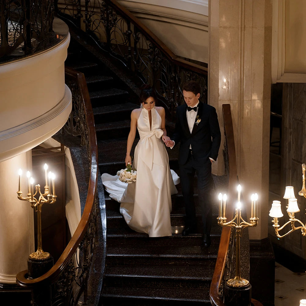 Feel like royalty in this Robe Oceane wedding dress. Handcrafted with luxurious satin, this halter high neck dress features a minimalist design for an effortlessly sophisticated look. The backless design with a large bow trailing the A-line silhouette is a timeless classic that will make you look and feel like a beautiful bride. Custom made and available in big sizes, make your special day even more special with this exquisite minimalistic yet sexy gown.