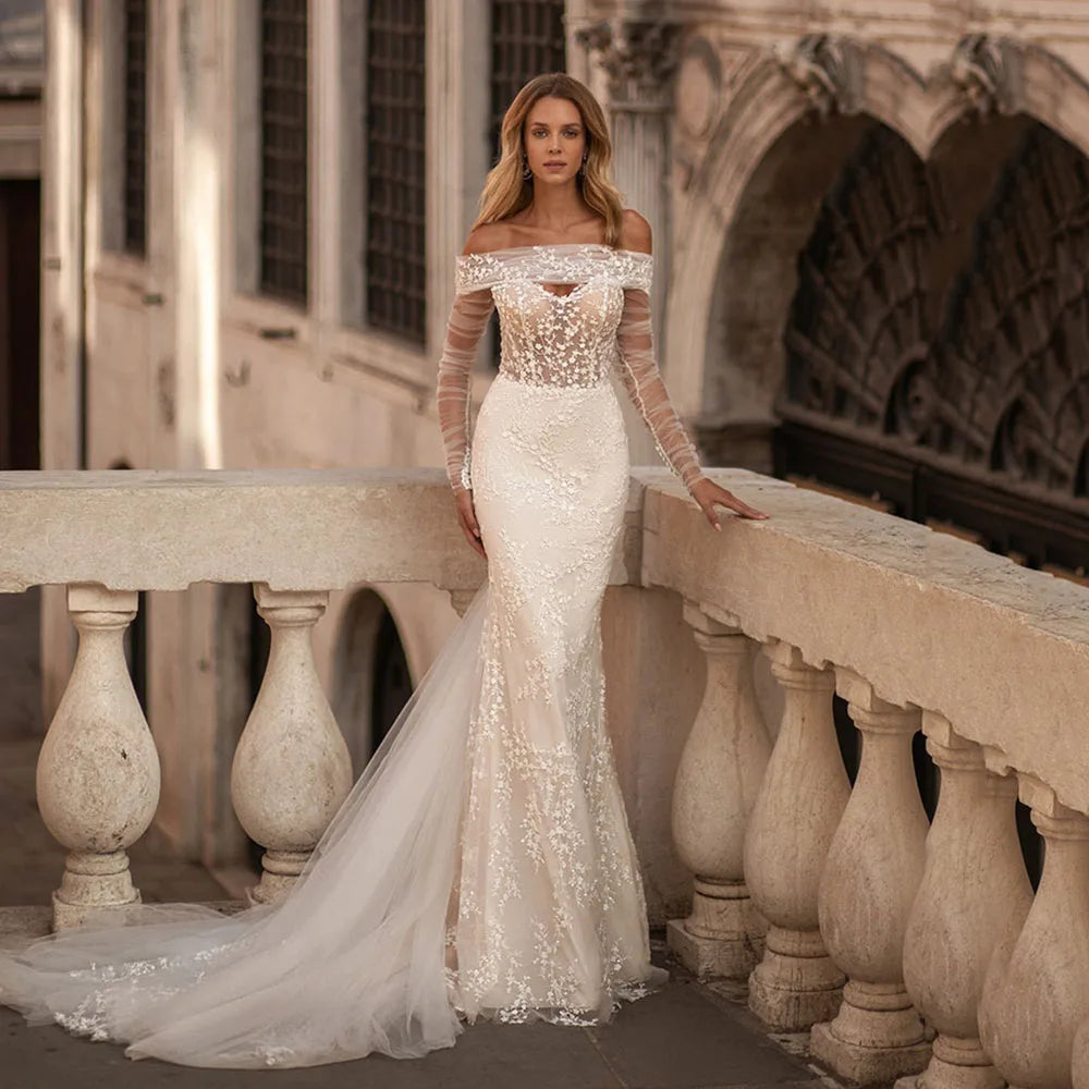 Elevate your bridal look with the exquisite Robe Viviette. This elegant bohemian gown features off-the-shoulder long sleeves, adding a touch of romance to your special day. The vintage design and intricate detailing make it the perfect choice for the stylish and sophisticated bride. Make a statement with Robe Viviette.