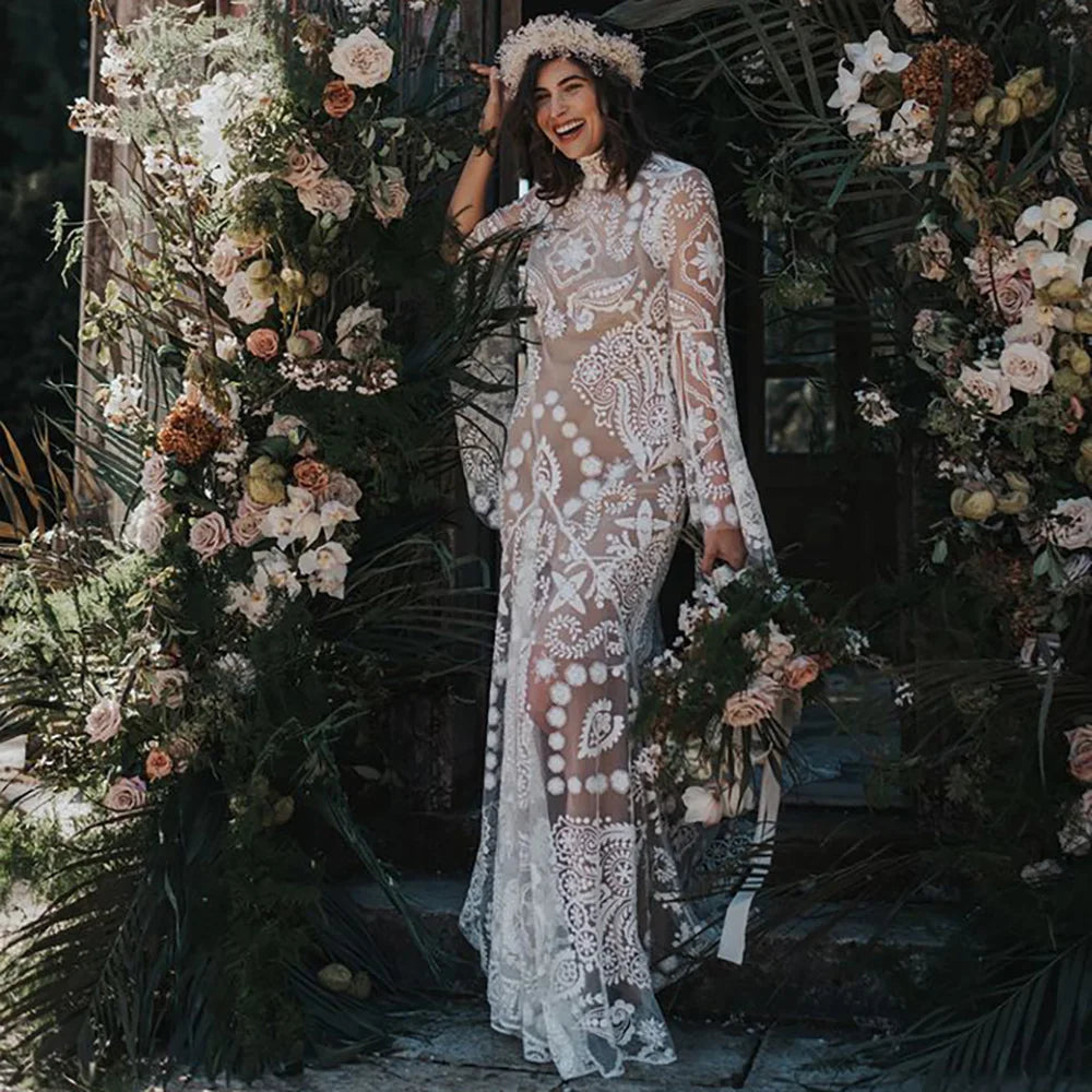 Expertly crafted for the modern and elegant bride, the Robe Anaise features delicate lace detailing and a sleek, form-fitting silhouette. Its long batwing sleeves and high neck add a touch of bohemian flair, while the custom made double slip with slit ensures comfort and movement on the big day. Complete your bridal look with this two-piece, backless sheath gown.