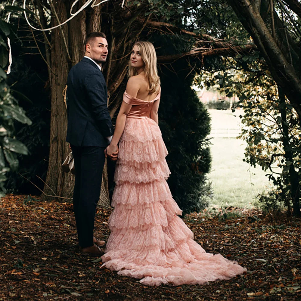 Elevate your wedding day in the exquisite off shoulder Robe Melissa. Crafted with delicate tiered lace in a dreamy mauve pink hue, this A-line custom-made gown is perfect for the plus-size bride. With a breathtaking long train and tutu details, this dress is a must-have for your elopement photoshoot.