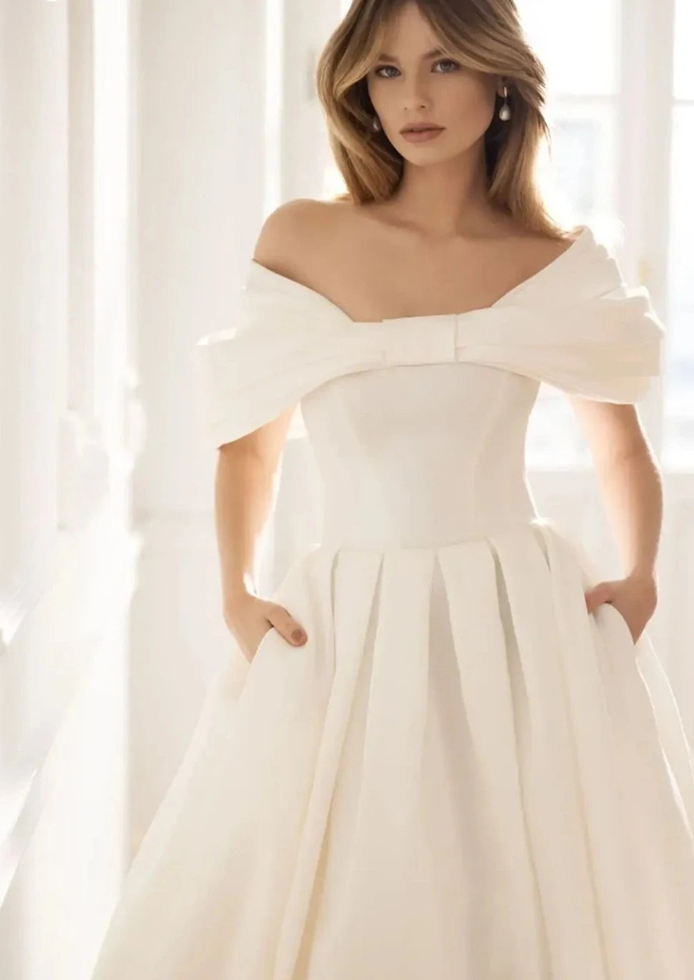 Introducing the Robe Elia - the perfect addition to your special day! This wedding dress features an elegant sweetheart neckline, delicate bow accents, and a romantic off the shoulder design. The A-line silhouette flatters every figure, while the ruched bodice adds a touch of sophistication.