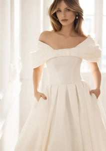 Introducing the Robe Elia - the perfect addition to your special day! This wedding dress features an elegant sweetheart neckline, delicate bow accents, and a romantic off the shoulder design. The A-line silhouette flatters every figure, while the ruched bodice adds a touch of sophistication.