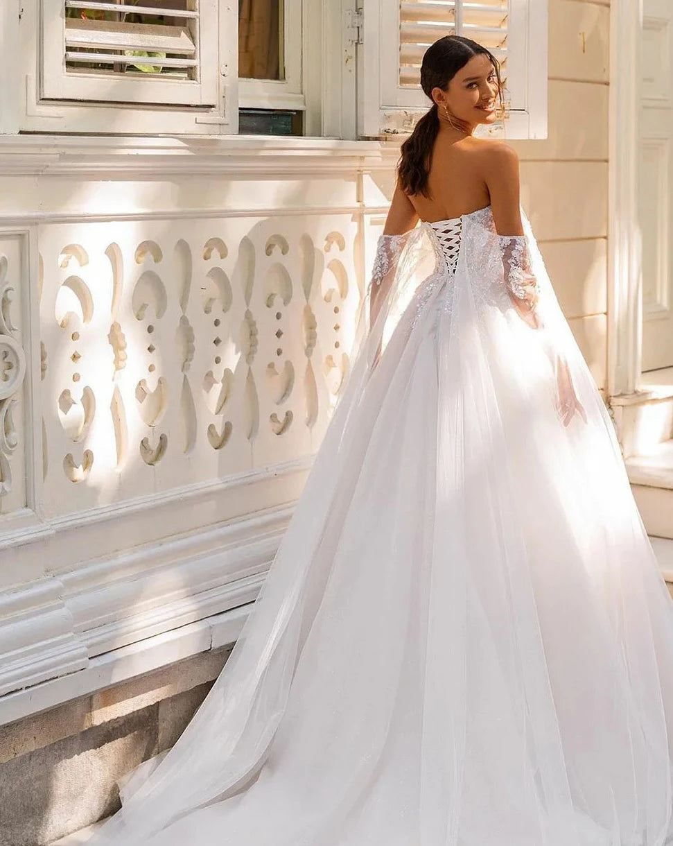 Indulge in pure luxury with the Robe Amia. This elegant off the shoulder A-line wedding dress boasts a sleeveless design that exudes sophistication. Adorned with vintage sequin lace applique and delicate tulle, this bridal gown is a work of art. Make a statement on your special day with the Robe Amia.