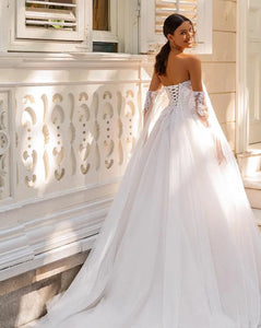 Indulge in pure luxury with the Robe Amia. This elegant off the shoulder A-line wedding dress boasts a sleeveless design that exudes sophistication. Adorned with vintage sequin lace applique and delicate tulle, this bridal gown is a work of art. Make a statement on your special day with the Robe Amia.