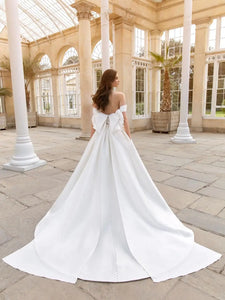 This 2-in-1 wedding dress offers versatility and style for a bride on her special day. It features a detachable ball gown with an off-shoulder design and a long, sheer tail for a dramatic entrance. The pleated bodice adds a touch of elegance and glamour, making it the perfect dress for any bride.