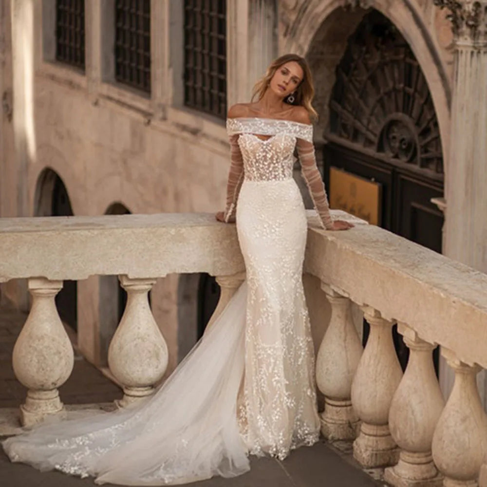 Elevate your bridal look with the exquisite Robe Viviette. This elegant bohemian gown features off-the-shoulder long sleeves, adding a touch of romance to your special day. The vintage design and intricate detailing make it the perfect choice for the stylish and sophisticated bride. Make a statement with Robe Viviette.