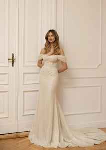 Slay the wedding game in the Robe Claretta! This stunning bridal gown features an elegant boat neckline and off the shoulder design, while the sheath silhouette and ruched details add a touch of sophistication. Get ready to turn heads down the aisle with this show-stopping piece.