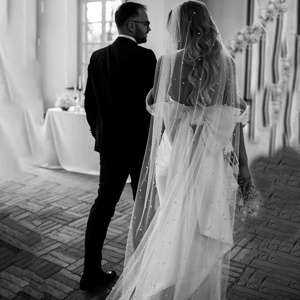 Introducing the Robe Rafaella - the perfect wedding dress for the modern bride. This elegant off shoulder sheath dress features a removable bow and is custom made to ensure the perfect fit. Made with thick satin, it offers a simple and timeless look while providing comfort and support. Say "I do" in style with the Robe Rafaella.