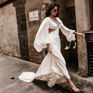 Indulge in the luxurious elegance of the Robe Suzanne. Featuring long bishop sleeves, an open back, and a side cutout, this custom-made wedding gown is made of flowing chiffon, accentuating every curve. With a sexy V-neck design, this dress is perfect for the modern bride looking for a simple yet stunning look.
