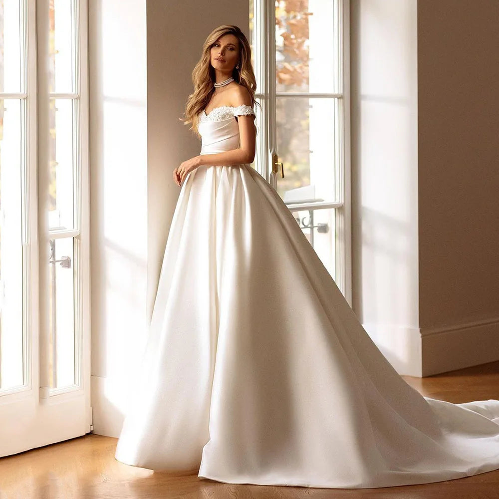 Indulge in luxury and sophistication with the vintage satin Robe Laverne. This off-shoulder A-line gown is crafted to perfection, featuring a backless design that will make you stand out on your special day. Be the epitome of elegance and grace with this timeless and romantic bridal gown.