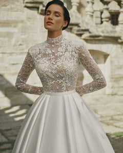 Indulge in timeless elegance with our Robe Prisca. This luxury boho wedding dress features a high neck, long sleeves, and intricate lace and sequin details. Made with satin, it's perfect for a sophisticated bridal look that will make you feel like a work of art.