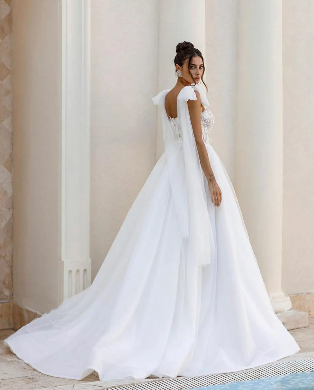 Introducing the Robe Allura - a stunning luxury lace wedding dress with delicate shoulder bows and elegant lace appliques. Designed in a flattering A-line silhouette, this dress is perfect for princess brides with a bohemian touch. Look and feel like a true wedding day princess in this breathtaking gown.