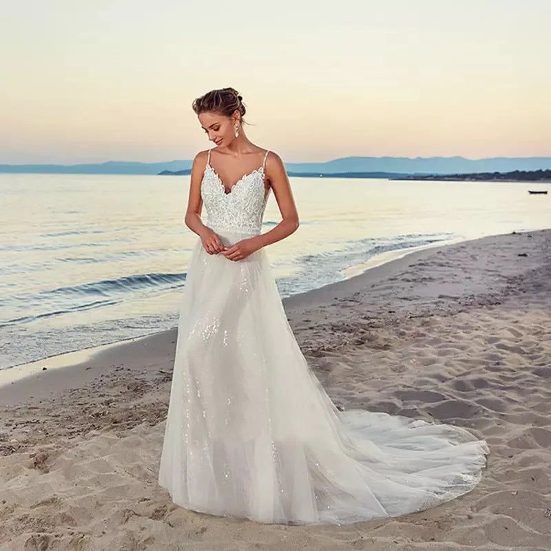 Make an unforgettable entrance on your special day with the Robe Geneva. Featuring new spaghetti straps, a V-neck design, and a backless silhouette, this exquisite beach bridal gown is adorned with delicate appliques. A shimmering court train adds timeless charm to the look. Soft and luxurious tulle will provide a fabulous fit for a picture-perfect wedding.