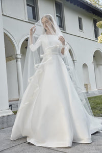 The Robe Magdalene is an elegant, a-line bridal gown fit for a princess. Its timeless design and flowing silhouette exude sophistication and grace. With its stunning appearance, this gown is perfect for any bride looking to make a statement on her special day.