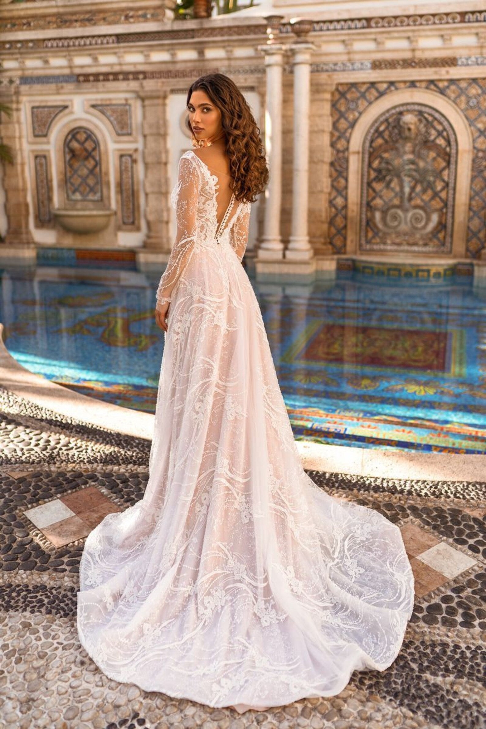 Be fearless on your special day with Robe Daisy! This stunning ivory gown features delicate lace and a show-stopping train, making you the standout bride. Shine in this long sleeve, a-line wedding dress and make a statement in every step!