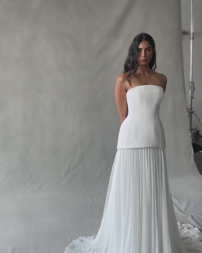 Experience luxury with the Clara Crepe Gown. Made from 100% satin silk crepe, this strapless gown offers a comfortable and elegant fit. The drop waist adds a touch of sophistication, making it the perfect choice for any special occasion. Available in a beautiful off-white color.