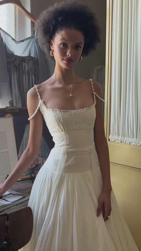 The Elizabeth Gown is an elegant empire silhouette featuring delicate pin-tucked lace and broomstick pleated silk tulle. A graceful drop waist creates a flattering, romantic line, while freshwater pearl straps add timeless sophistication. The intricate lace detailing and flowing tulle combine classic bridal elegance with refined craftsmanship. Complete the look with our coordinating lace pin-tucked gloves for a cohesive, polished ensemble.